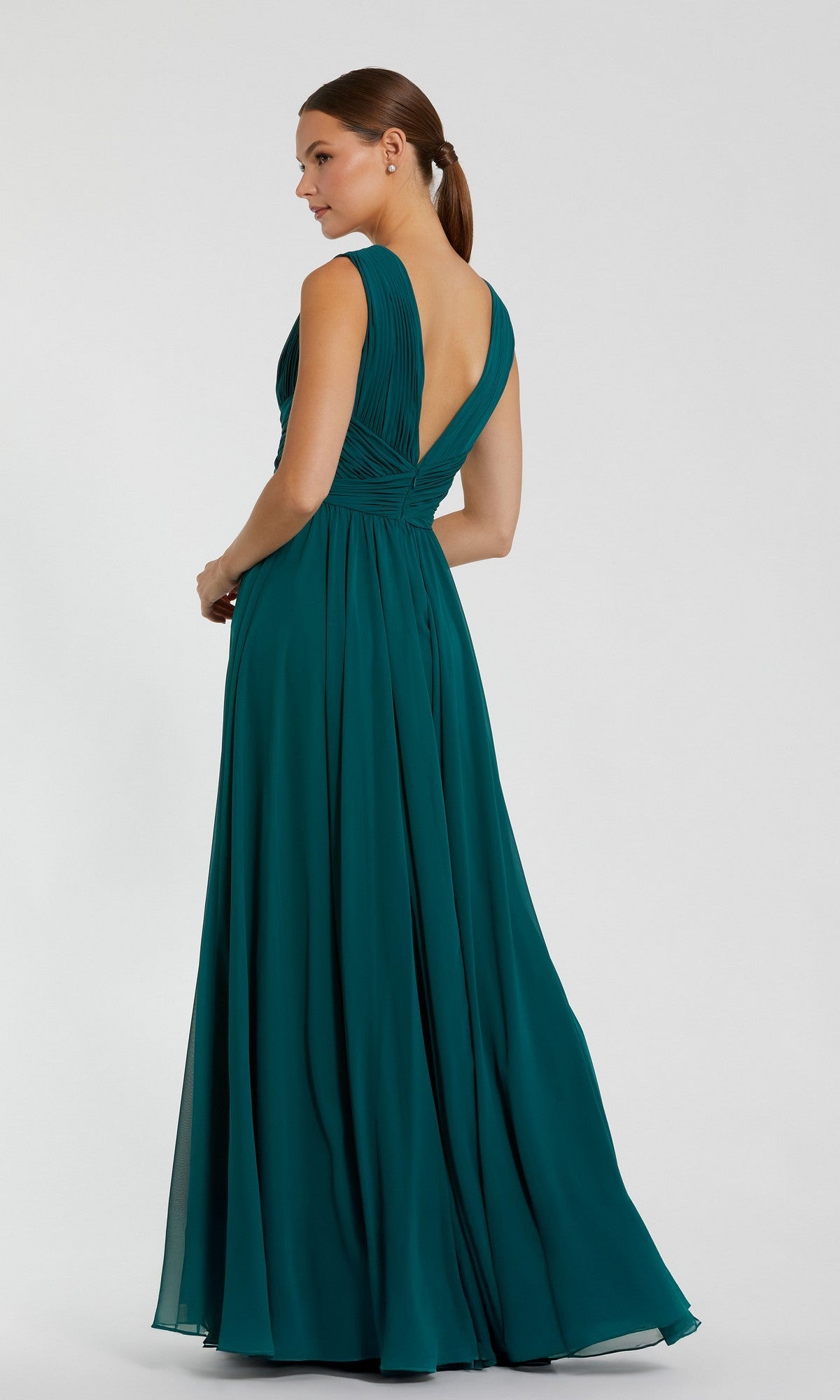 A woman stands sideways, wearing the Mac Duggal 11585 long formal dress—a sleeveless, floor-length teal gown with a deep V-back and flowing skirt.